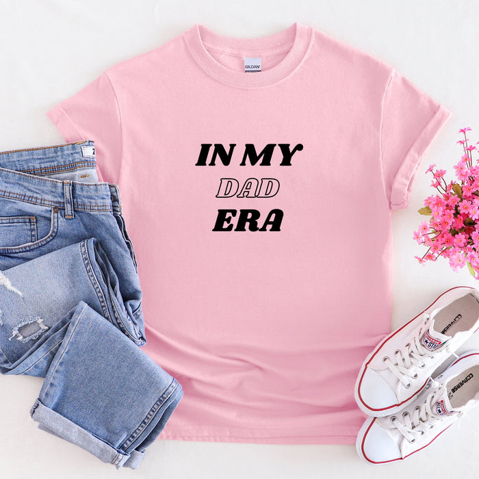 a pink shirt that says in my dad era next to a pair of jeans and