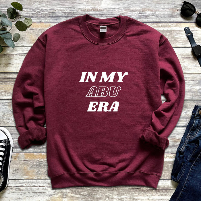 a maroon sweatshirt with the words in my aru era printed on it