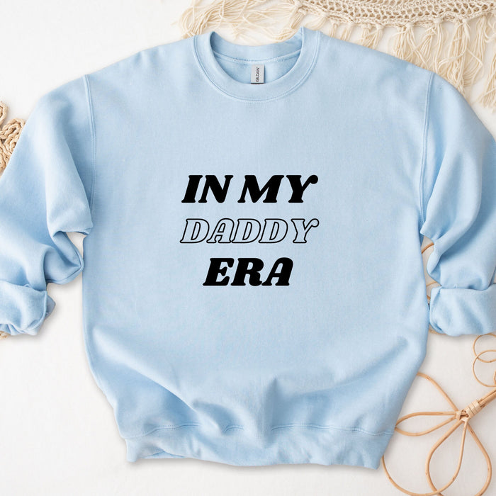 a light blue sweatshirt that says in my daddy era